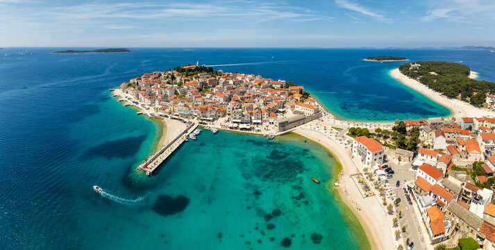Aerial panoramic view with scenic town and beaches of Primosten in Croatia, famous and picturesque tourist resort at Adriatic sea coast.