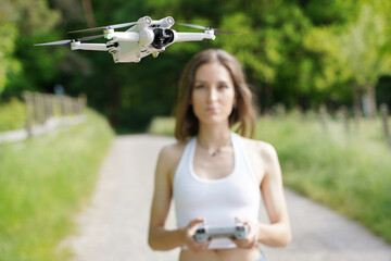 Young woman in nature controlling camera drone with remote control