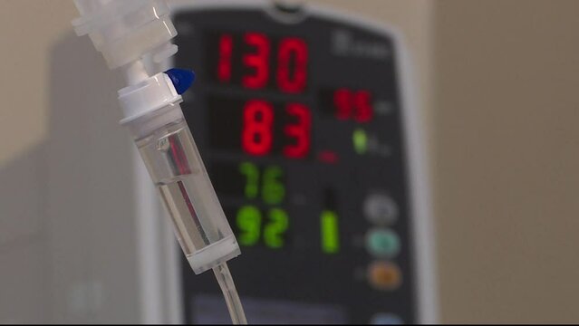 IV drip in the surgical operating room. IV drip system for intravenous infusion of medicines on the background of the surgical monitor display.