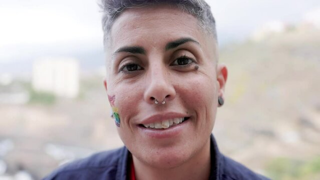 Happy gay lesbian woman smiling on camera outdoor at LGBT pride parade