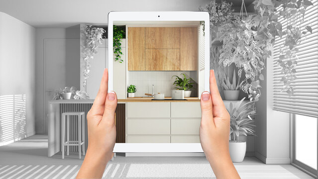 Hands holding tablet showing minimal kitchen, total blank project background, augmented reality concept, application to simulate furniture and interior design products