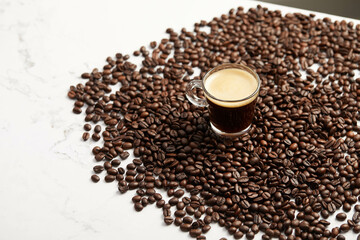 Cup of espresso coffee and coffee beans, on white marble table