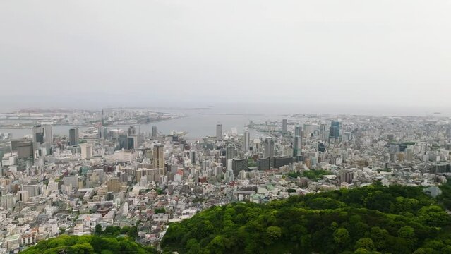 Flying from sprawling Kobe City over green forest on Mt. Rokko