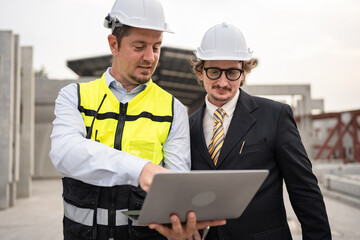 Portrait two caucasian engineer man working with notebook computer at precast site work	