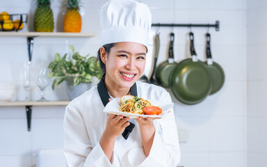Portrait beautiful Asian professional female chef wearing white uniform, hat, showing plate of...