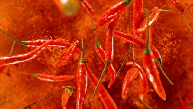 Super slow motion of flying and rotating red chilli peppers. Filmed on high speed cinema camera, 1000 fps, placed on high speed cine bot, following the target. Black background. Speed ramp effect.
