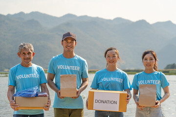group of diverse volunteer carrying donation box raising money charitable working together for...