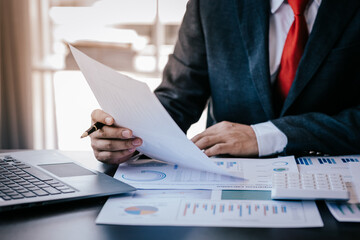 Close up work of businessman or accountant using calculator and laptop while analyzing business report in workplace financial planning and accounting concept