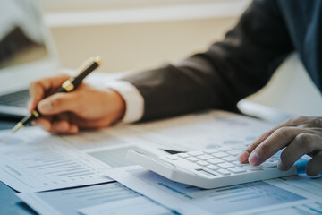 Close up work of businessman or accountant using calculator and laptop while analyzing business report in workplace financial planning and accounting concept