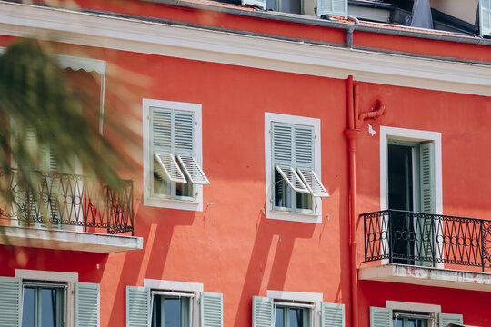 Fototapeta Bright red southern facades of Nice and typical windows with shutters, contrasting color