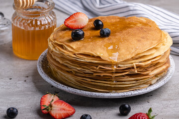 Large stack of traditional thin Russian pancakes on a plate close-up