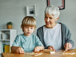 grandchild family child grandparent grandmother game playing boy stick pick up board board game...
