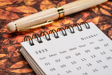 October 2023 - closeup of a small desktop calendar with a pen, time and business concept