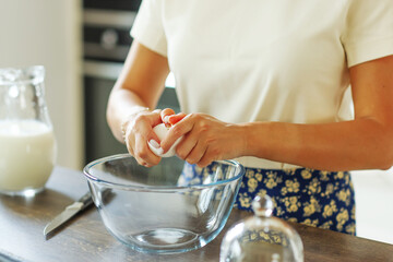 Close up hand breaking an egg to the dough for pancake. Ingredients for focaccia, pie, pizza, ravioli, pasta. bakery, cookbook, cooking blog.