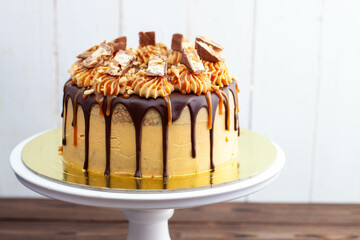 Gorgeous snickers cake with peanut butter cream, melted chocolate, candy bars and salted caramel