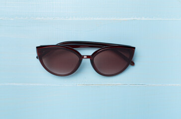 Sunglasses on wooden background, top view.