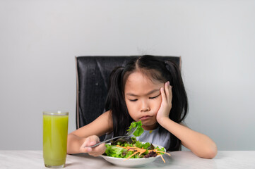 Little asian cute girl refuses to eat healthy vegetables.Nutrition & healthy eating habits for kids concept.Children do not like to eat vegetables.