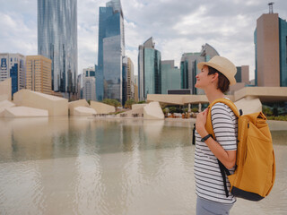 travel to the United Arab Emirates, Happy young asian female traveler with backpack and hat in big city of Abu Dhabi. Qasr al-Hosn first structure of the city