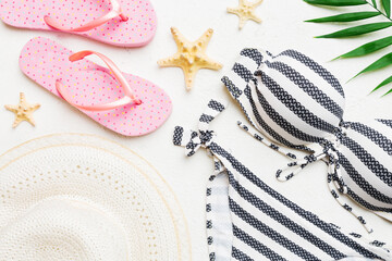 Woman swimwear and beach accessories flat lay top view on colored background Summer travel concept. bikini swimsuit, straw hat and seasheels. Copy space Top view