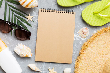 Blank writing book with summer beach accessories on background, copy space. Flat lay with copy space
