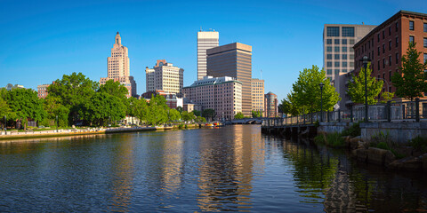 Downtown Providence skyline, city park, and building reflections at sunrise over the river in Rhode Island © Naya Na