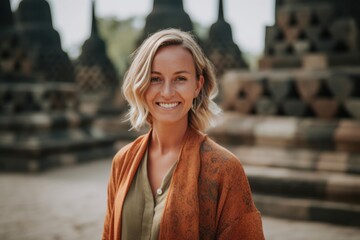 Fototapeta premium Lifestyle portrait photography of a pleased woman in her 30s that is wearing a chic cardigan at the Borobudur Temple in Magelang Indonesia . Generative AI