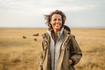 Happy young woman walking in the middle of a field and smiling.