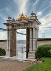 Marble gate with decorated open door leading to the Bosphorus Strait, with Bosphorus Bridge in the background, located at Beylerbeyi Palace, Istanbul, Turkey. Text above translate: In the name of God