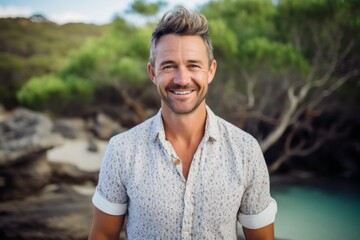 Naklejka na ściany i meble Portrait of smiling man standing on the beach on a sunny day