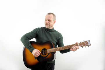 Picture of a guitarist, a man playing a guitar while sitting in a natural garden,music concept. High quality photo