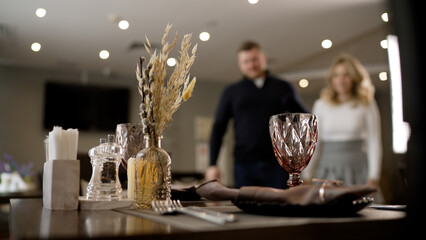 A young guy and a girl walk into a restaurant. Beautiful couple in love in a cozy restaurant. A reserved table for a date. The guy brings the girl to a restaurant at a table.