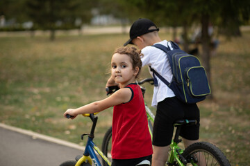 Obraz premium Two little boy and girl cyclists riding their bikes and enjoy having fun. Kid outdoors sport summer activity.