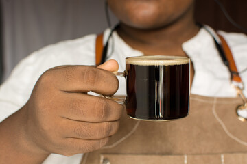 Fototapeta na wymiar Barista holding a cup of espresso, Espresso in a glass cup, foamy top of coffee