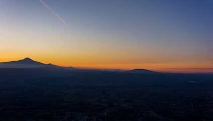 Sunrise in mountain valley, skyline and silhouette of mountain in horizon, orange and blue sky