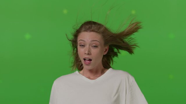 Caucasian girl in front of TV screen getting blown away. Cinema concept with chroma key.