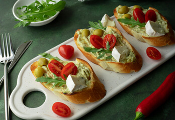 Bruschetta with guacamole, tomatoes, cheese, olives and greens
