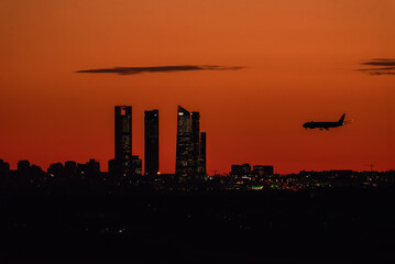 Madrid, Spain. March 23Th, 2023. Skyline of Madrid at sunset with a plane landing.