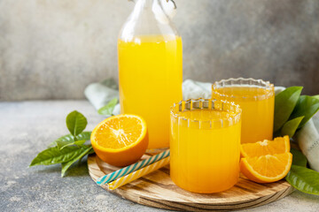 Ripe oranges and two glasses of fresh juice squeezed orange juice on a stone tabletop. Copy space.