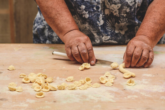 Fototapeta Local woman in the street of Bari old town making orecchiette or orecchietta, handmade pasta made with durum wheat and water typical of Puglia or Apulia, Italy, close up