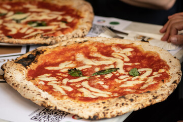 Friends eating hot pizza Margherita with tomato sauce, mozzarella and basil in a pizzeria or...