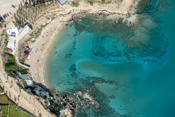 Drone aerial of beach umbrellas and people swimming in the sea. Summer holidays in the sea.