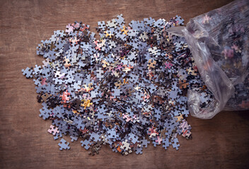 Many details of the cardboard puzzle are scattered on the table.Assemble a complex puzzle.A picture...