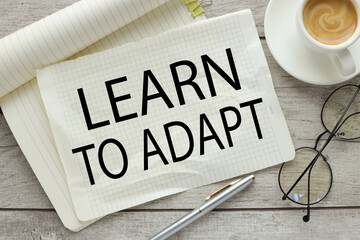learn to adapt. large notepad with text near cup of coffee and glasses