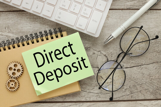 direct deposit text on note on notepad near computer keyboard. Business concept image