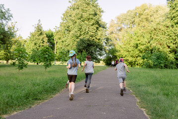 Children running through the park on a warm summer day, rear view
