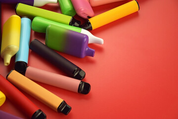 Set of multicolor disposable electronic cigarettes on a red background.