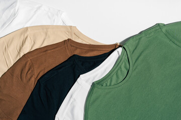 White, beige and green t-shirts laid out on a white isolated background. The concept of choosing...