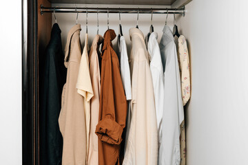 Summer clothing hangs on hangers in the closet horizontal image. Background for your design. The concept of updating the wardrobe and compact storage of things at the home