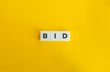 Bid Word on Block Letter Tiles on Yellow Background. Minimal Aesthetics.