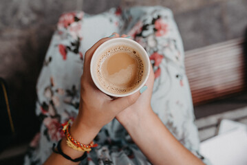 Steaming cup of coffee in the hands of a woman.